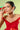 A woman in a red dress wearing Joud's diamond necklace, earrings and ring, holding a green gift box